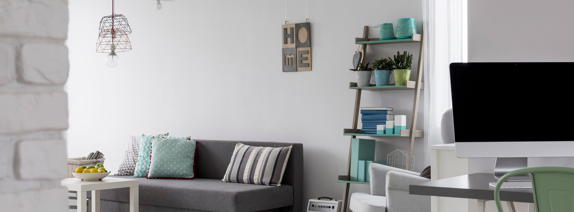 Light home interior with sofa, wall storage, simple desk and computer, panorama