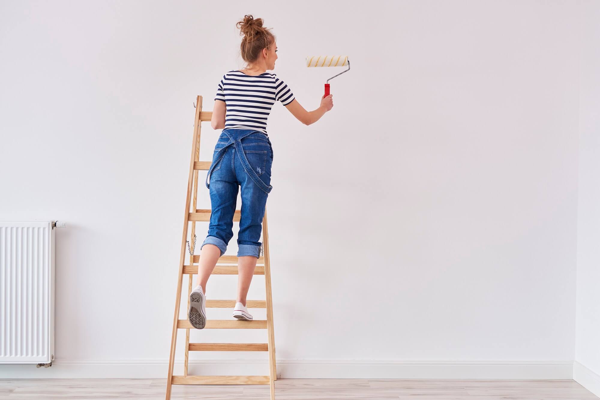 Rear view of woman with paint roller painting wall