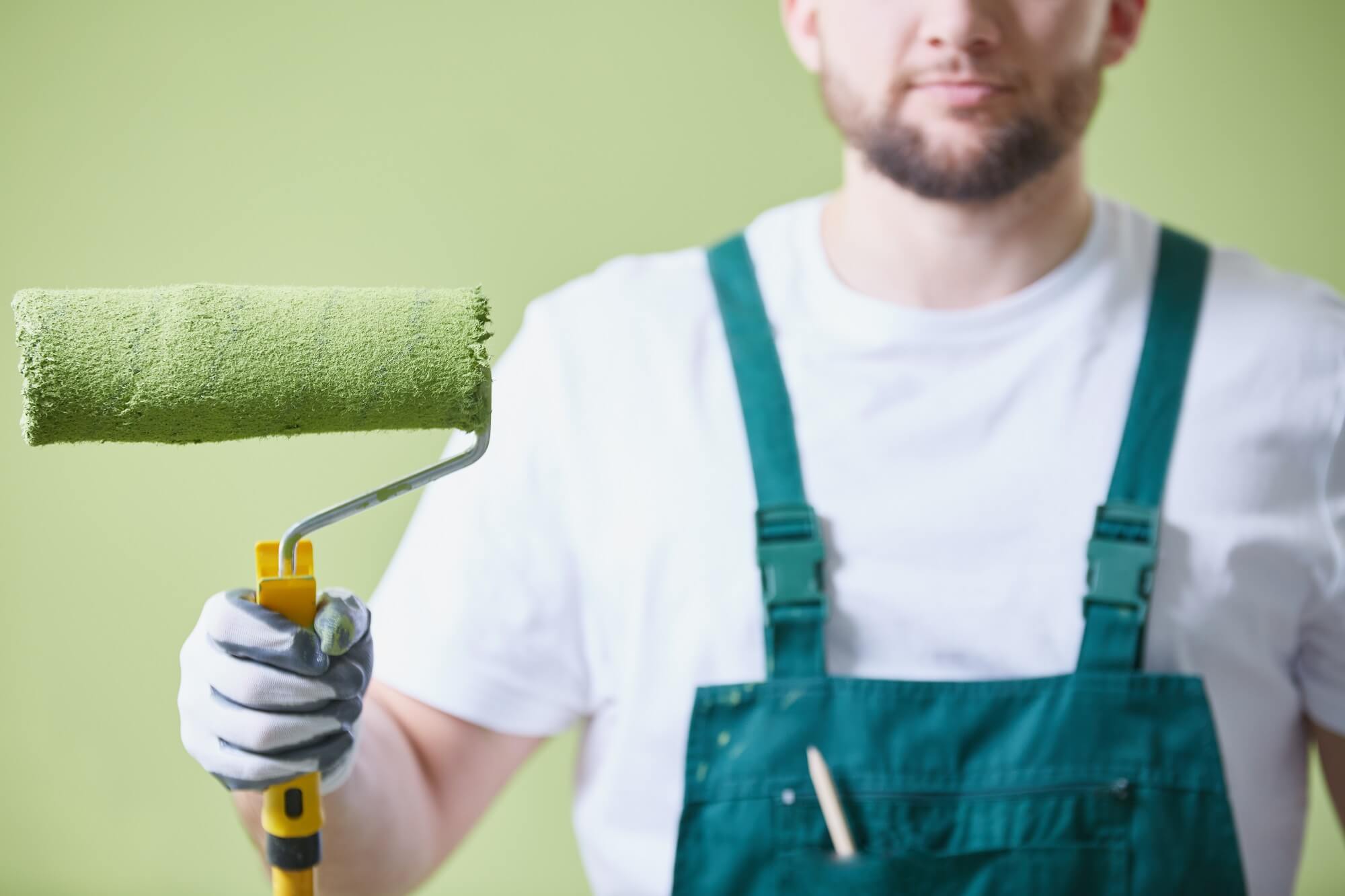 Man holding green paint roller prepared to paint the room