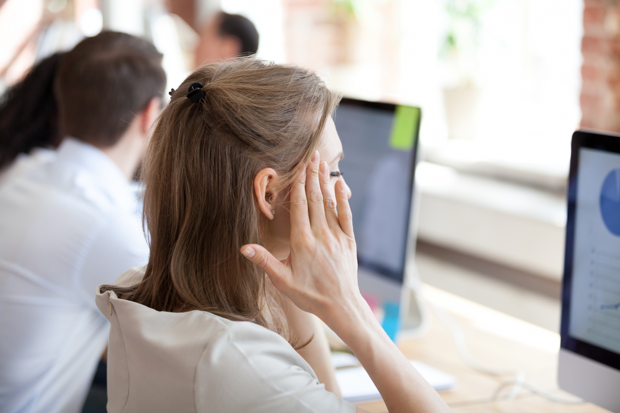 Stressed female employee massaging temples suffering from headache working too long at computer