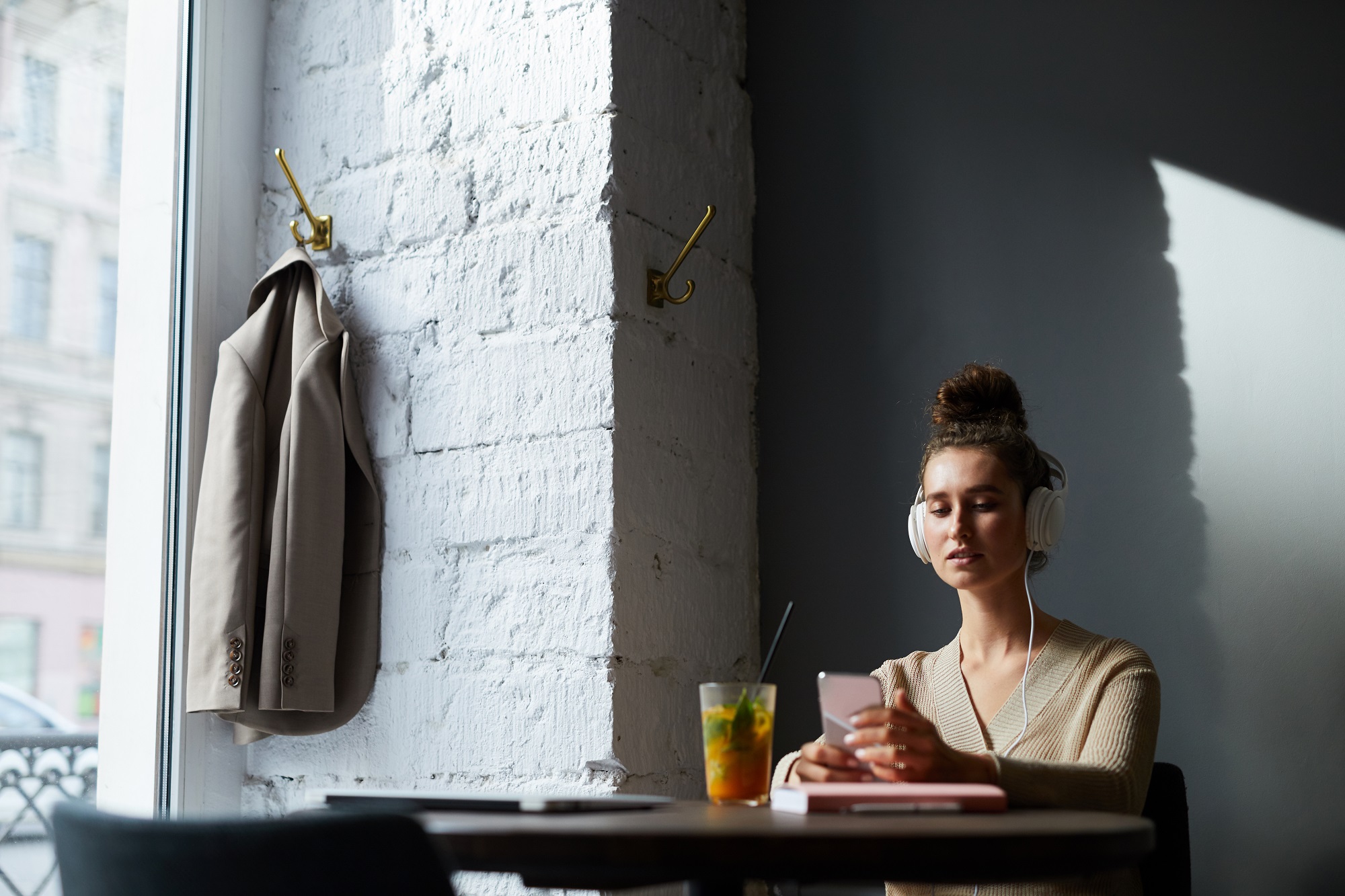 A pretty young woman using headphones looking through content on her smartphone