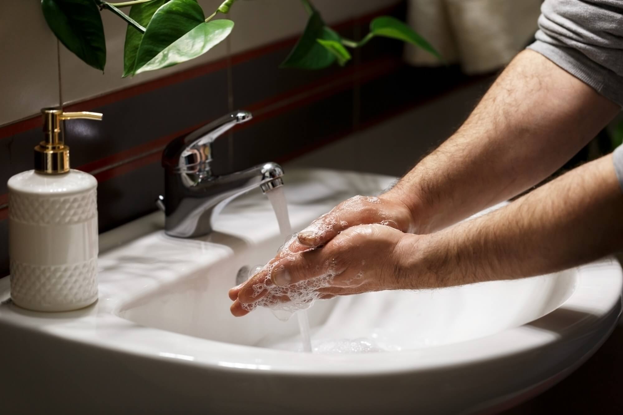 Man washing hands with soap under the fauset in the modern bathroom 