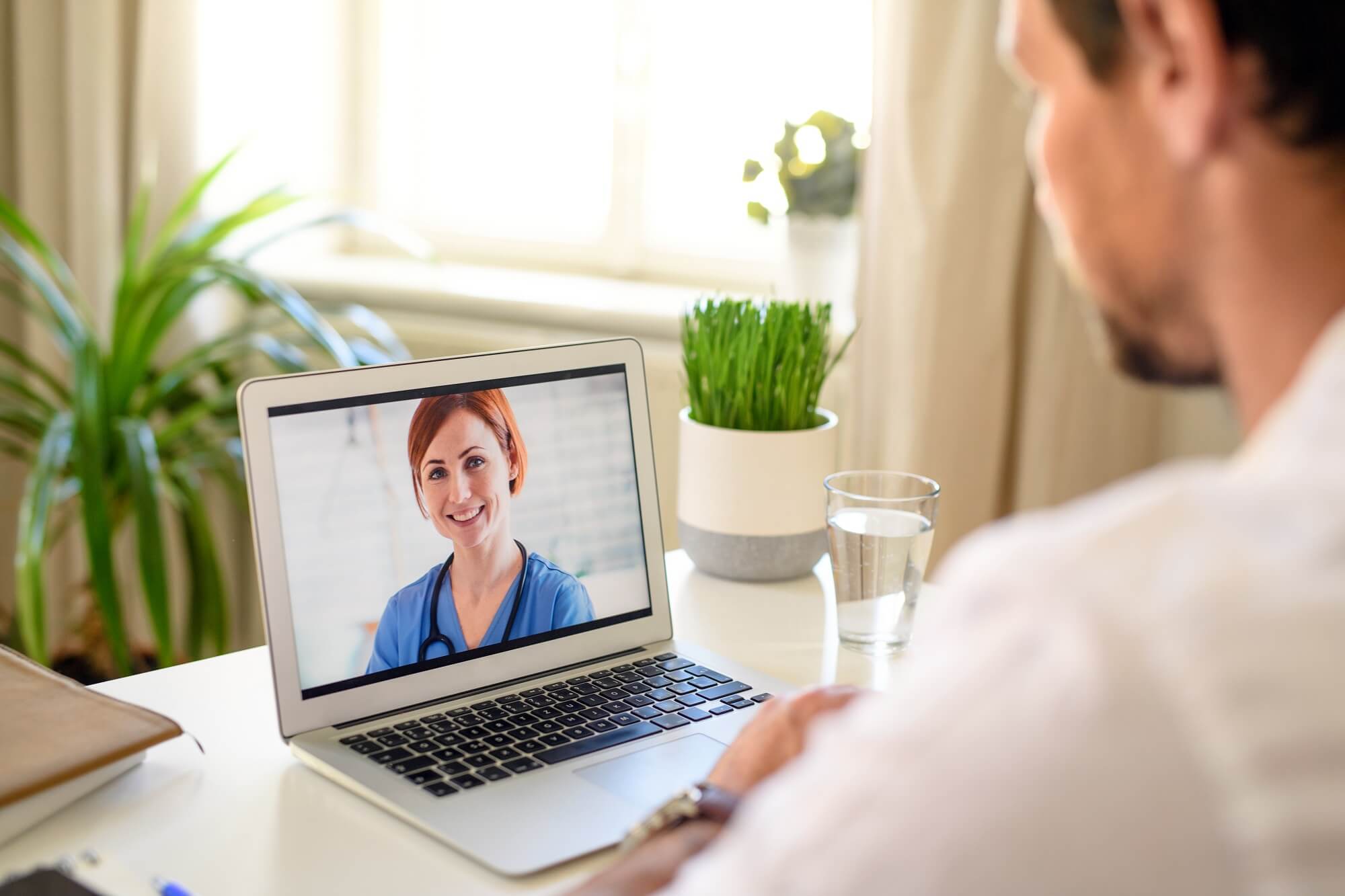 Mature man having video call with doctor on laptop at home