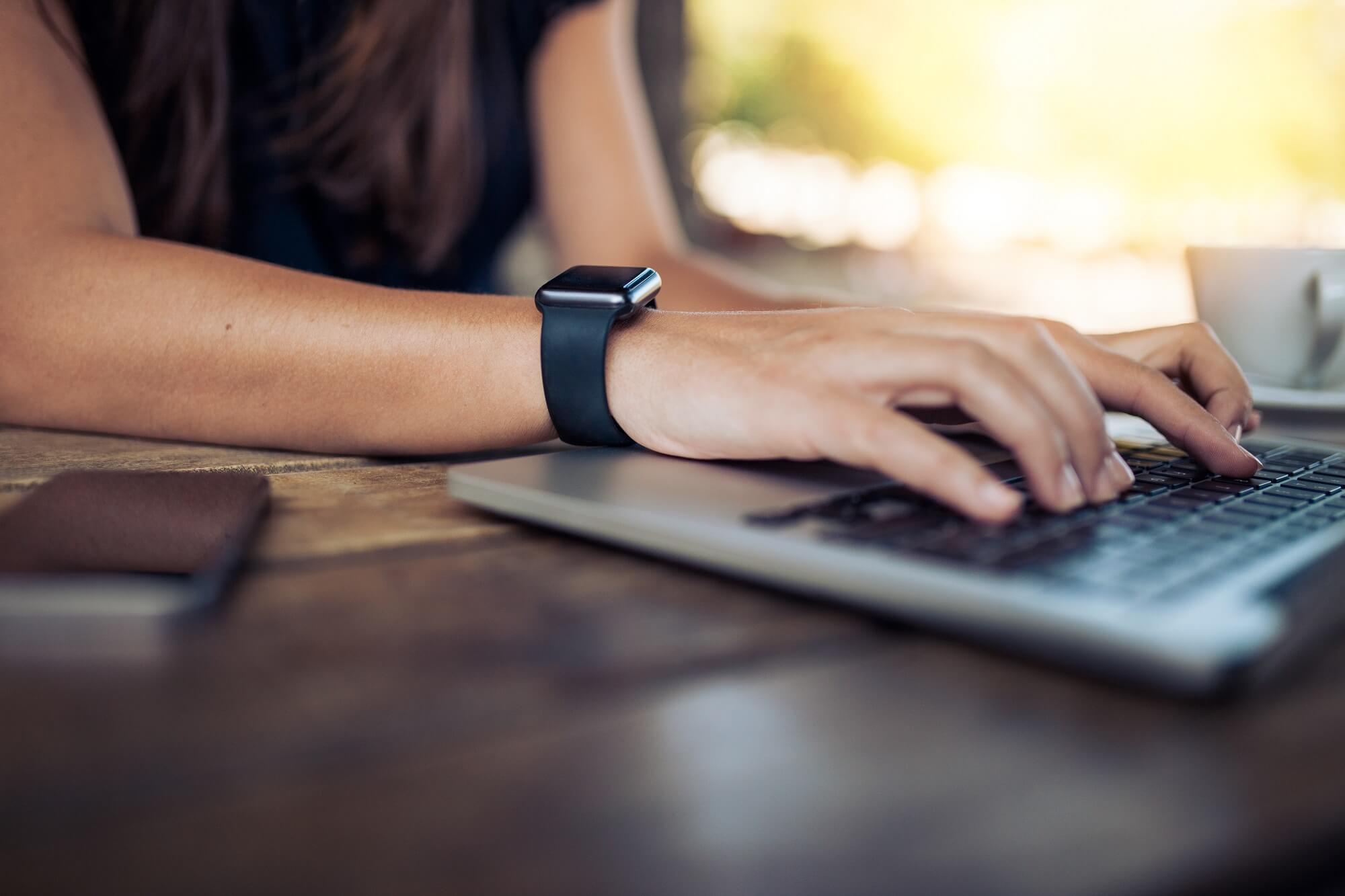 Hands of woman wearing smartwatch on the keyboard