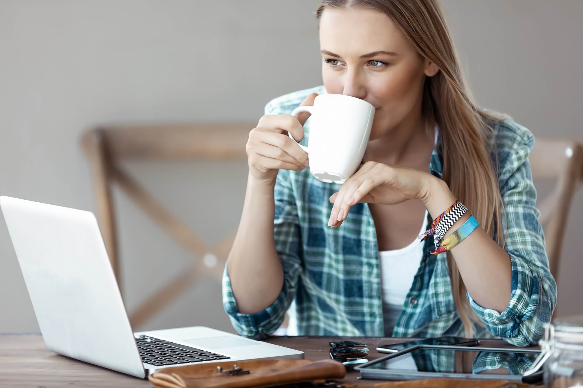 Female with Pleasure Drinking Coffee and Working on the Laptop