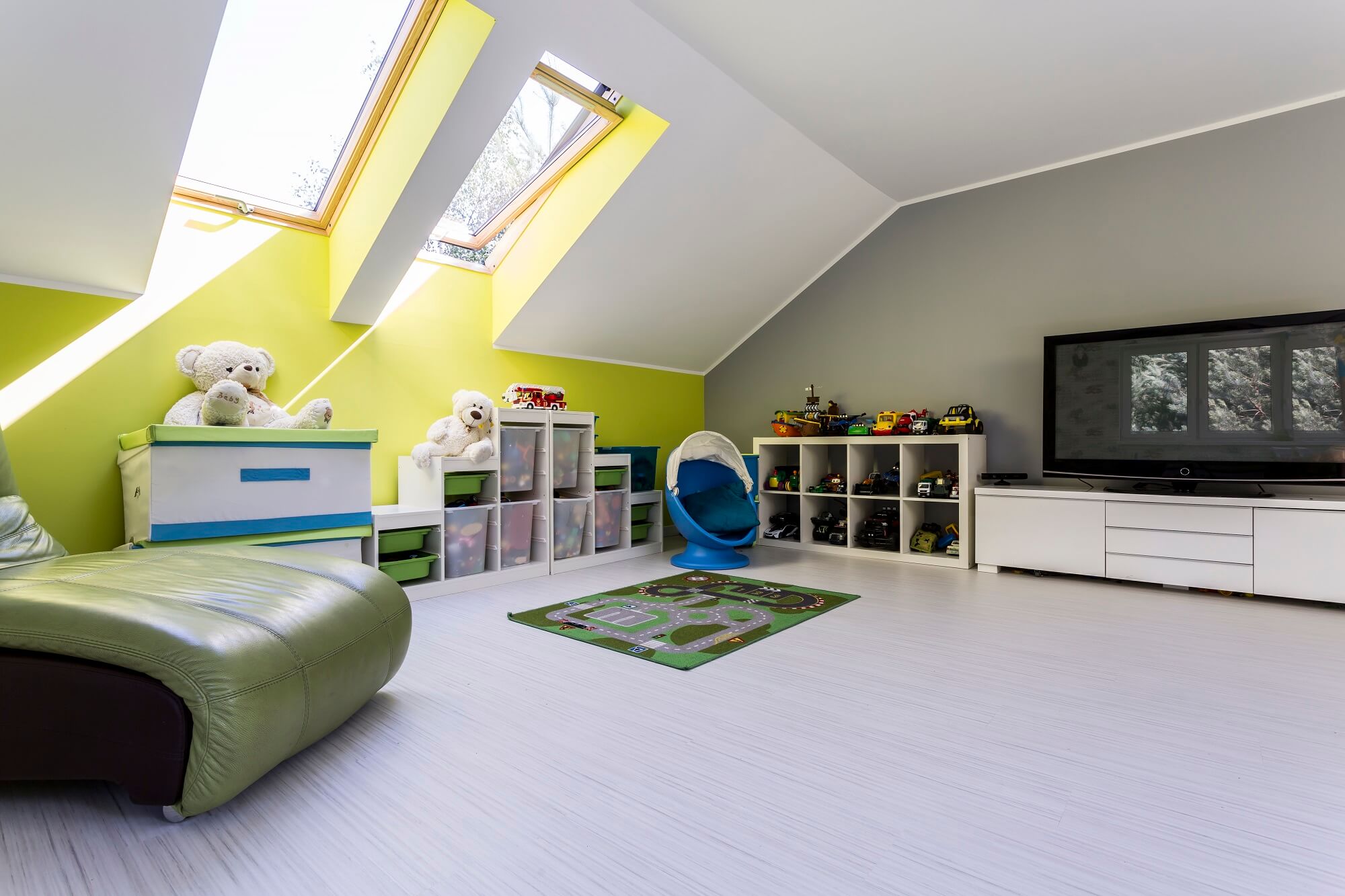 Child room at the attic with TV set, bed, chest of drawers and toys