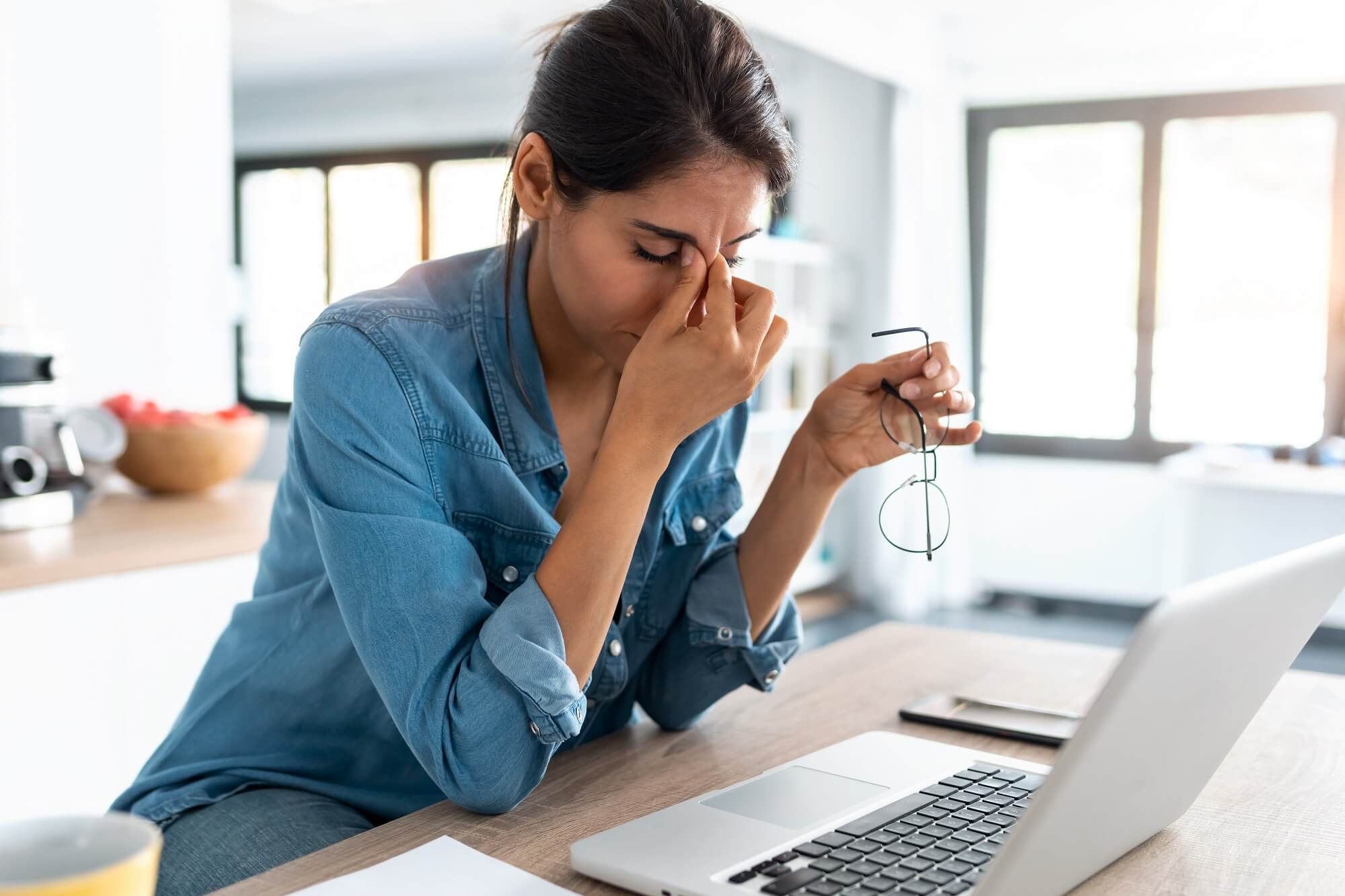 business woman doing work from home on laptop looking overwhelmed with productivity