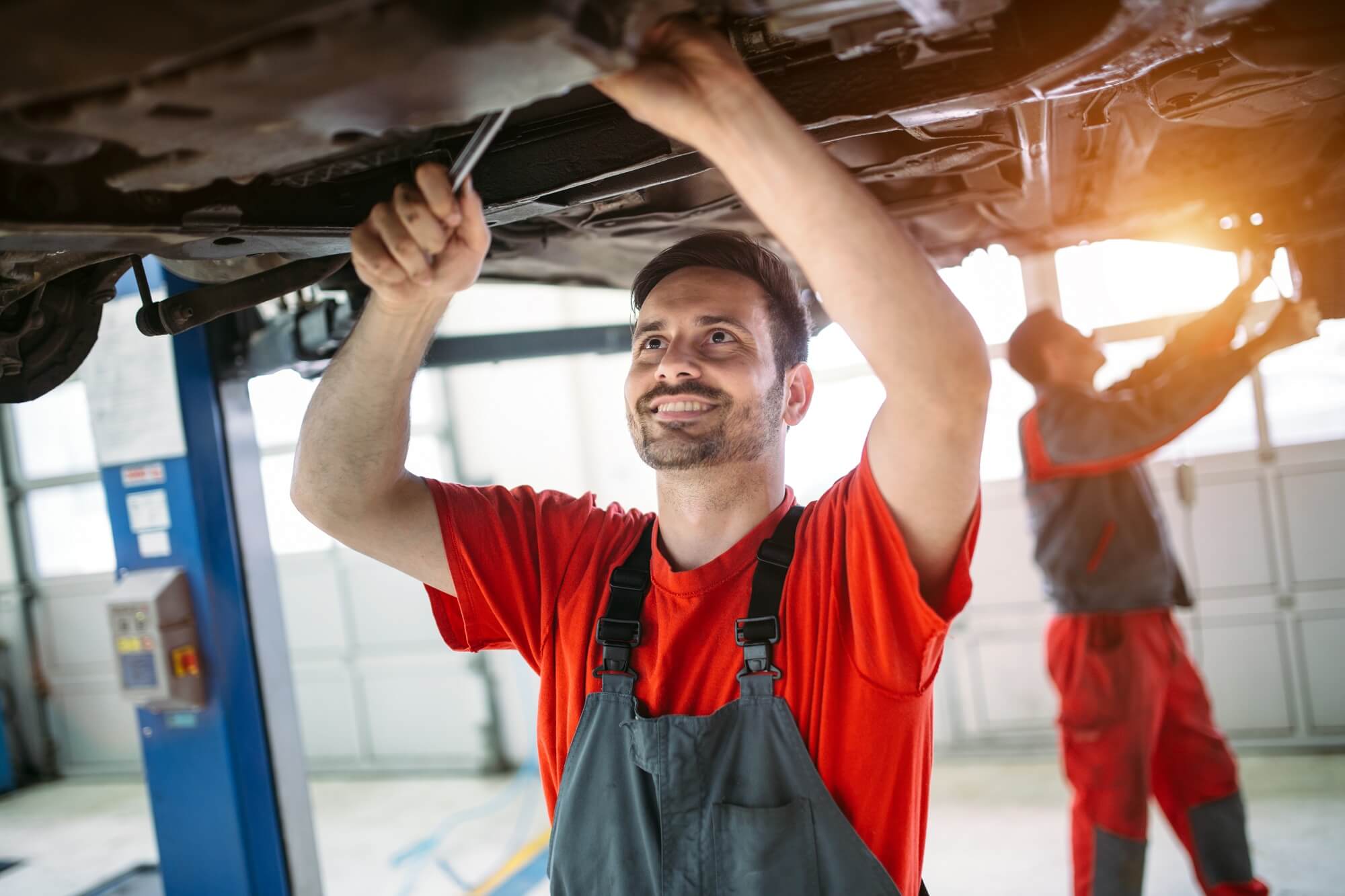 Car mechanic changing motor oil in automobile engine at maintenance repair service station