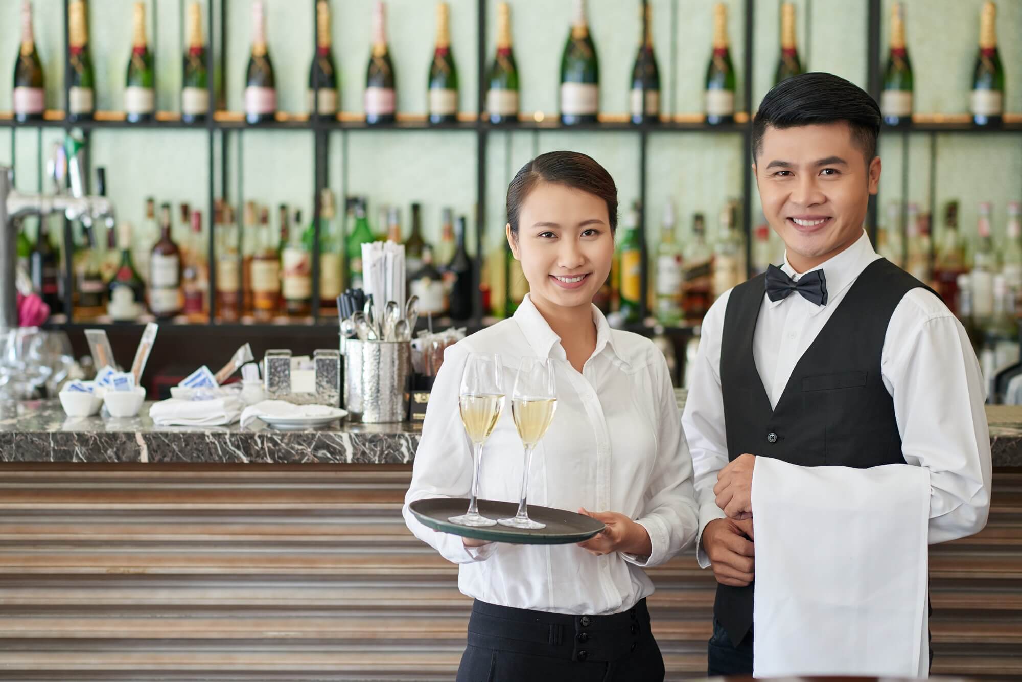 Smiling waiter and waitress with drinks and towel