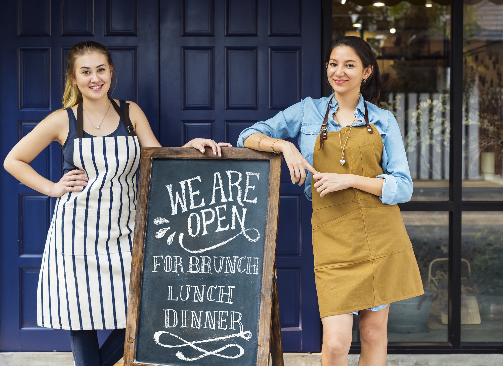 Cheerful business owners standing with open blackboard