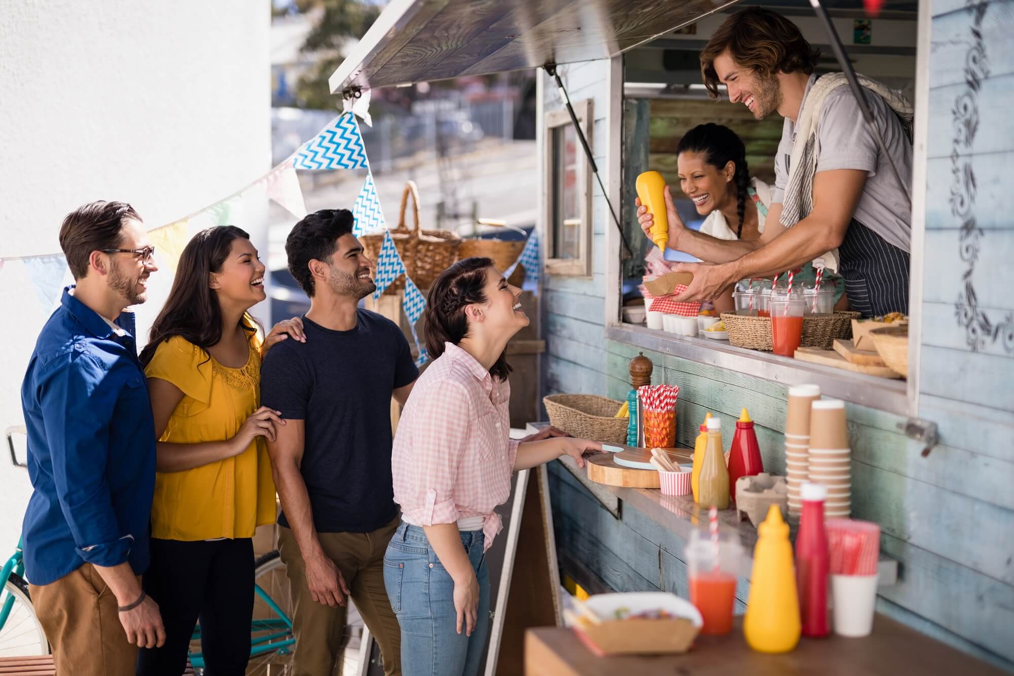 Smiling waiter serving customers at counter in food truck 