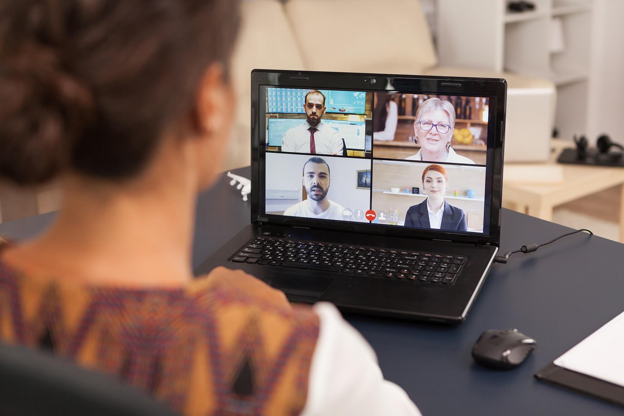 Woman talking with work colleagues on video call using computer from home.