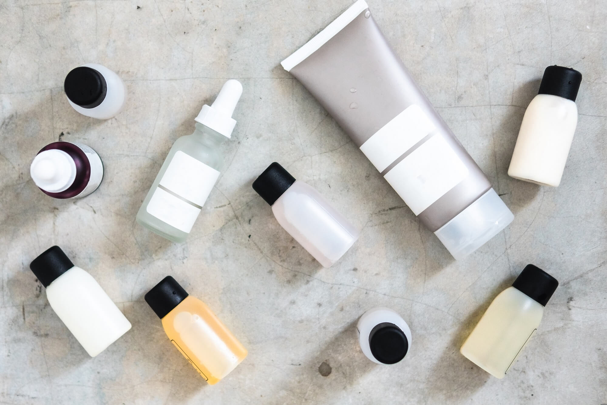 Bottles and tubes with salon cosmetic products from above on concrete table