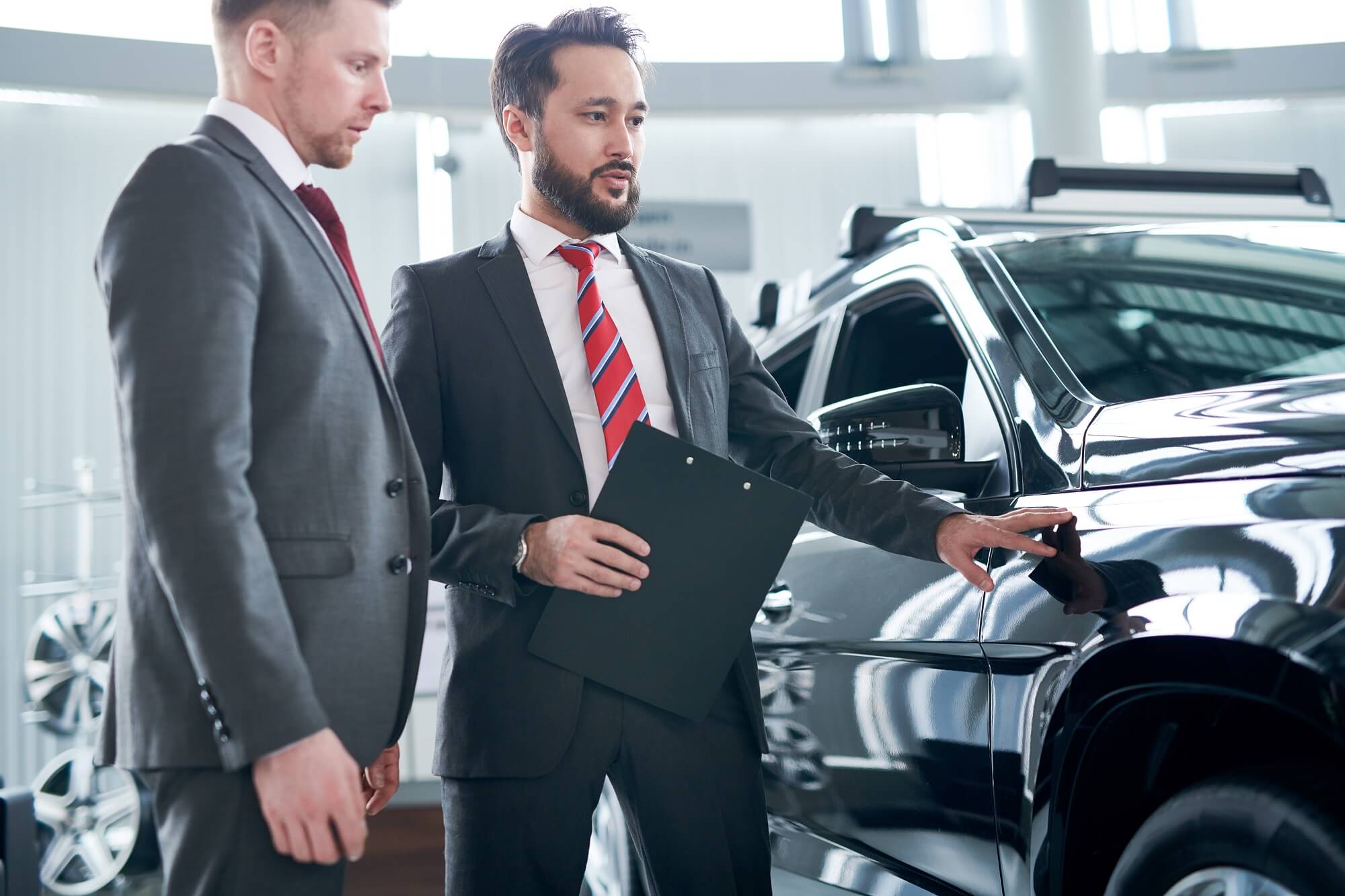 Professional sales person showing car to customer 