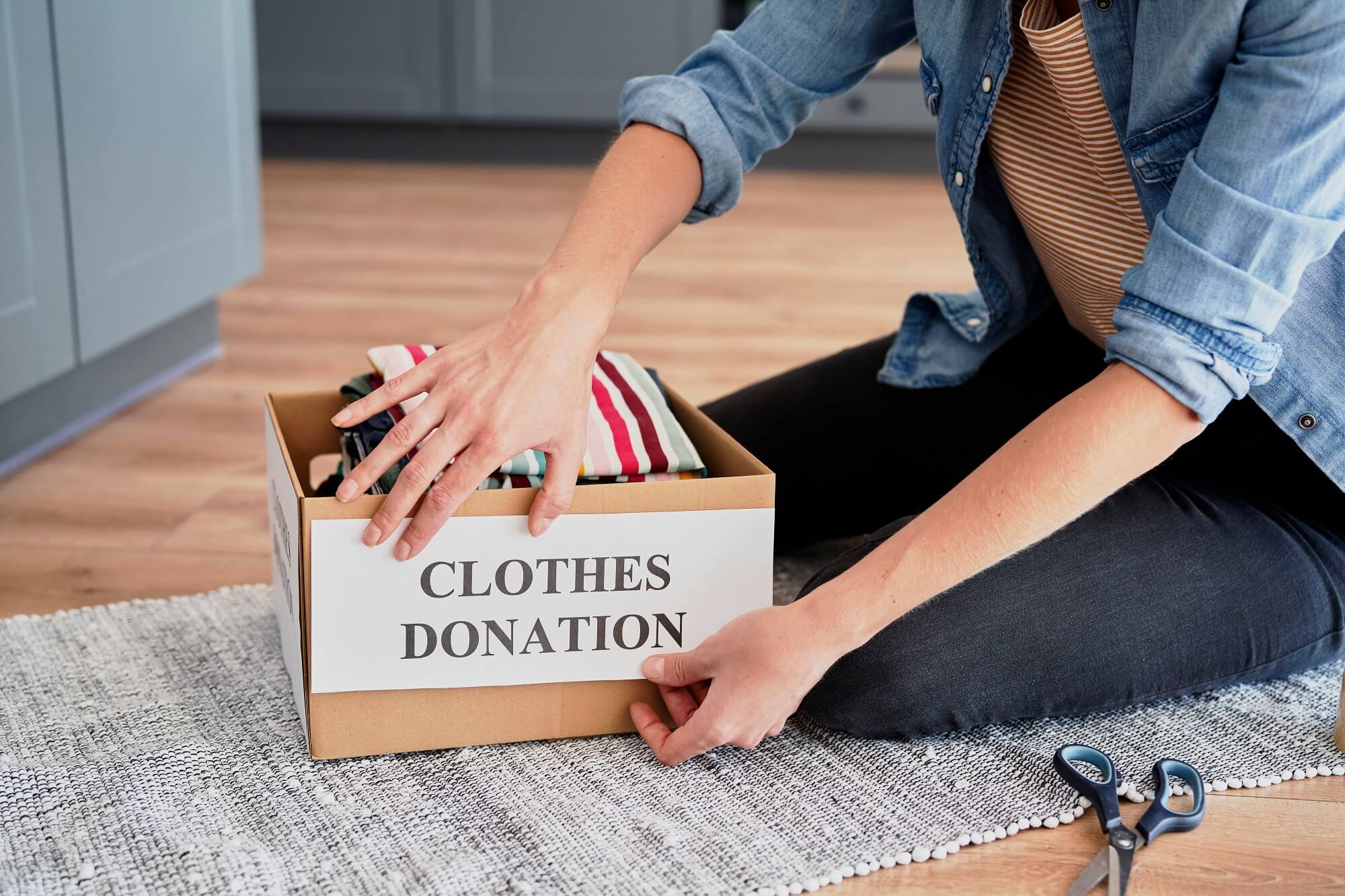 Woman preparing box for clothes donation