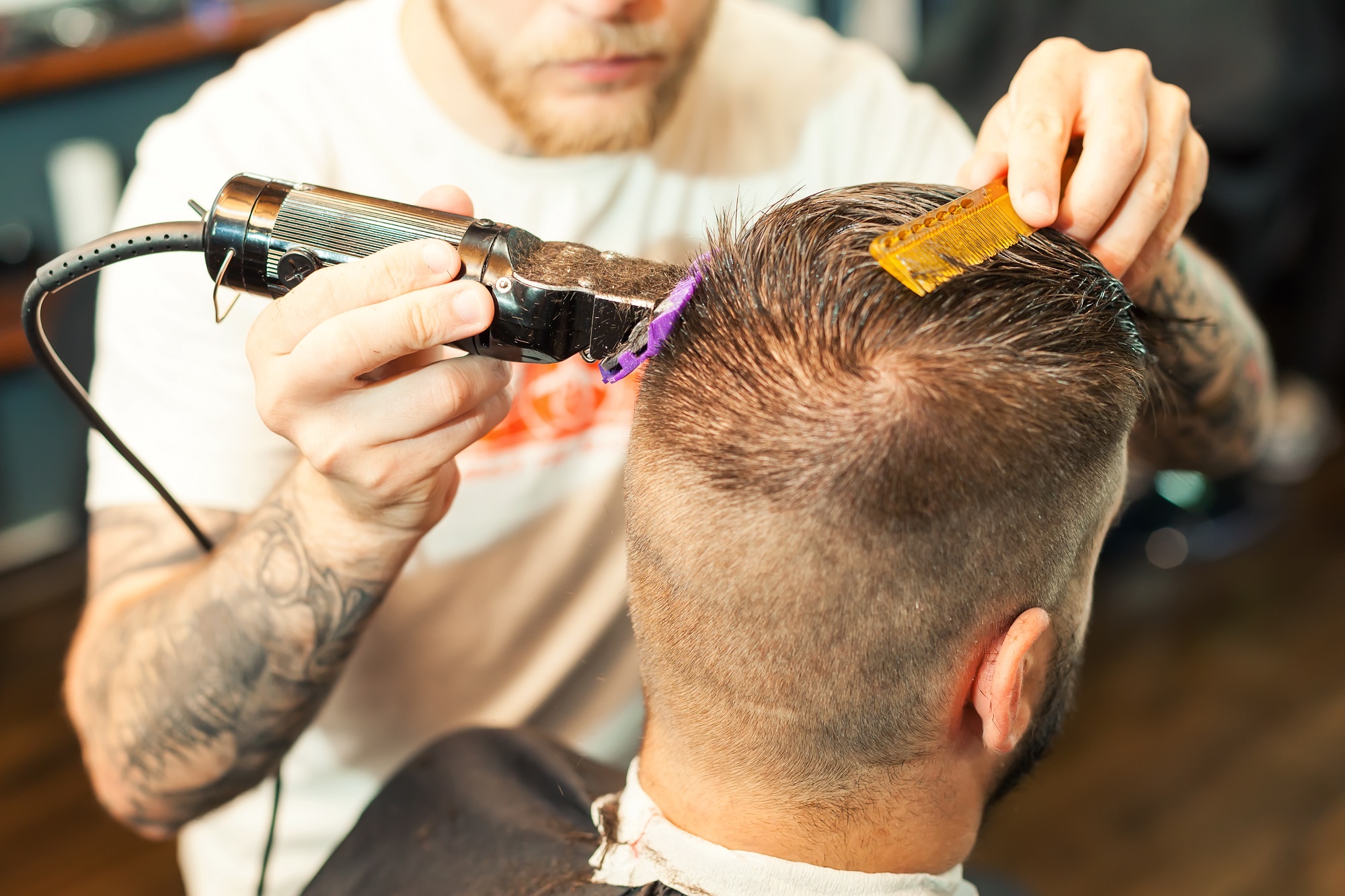 young man having hair dress, barber working with hair clipper at  local mobile hairdresser shop 