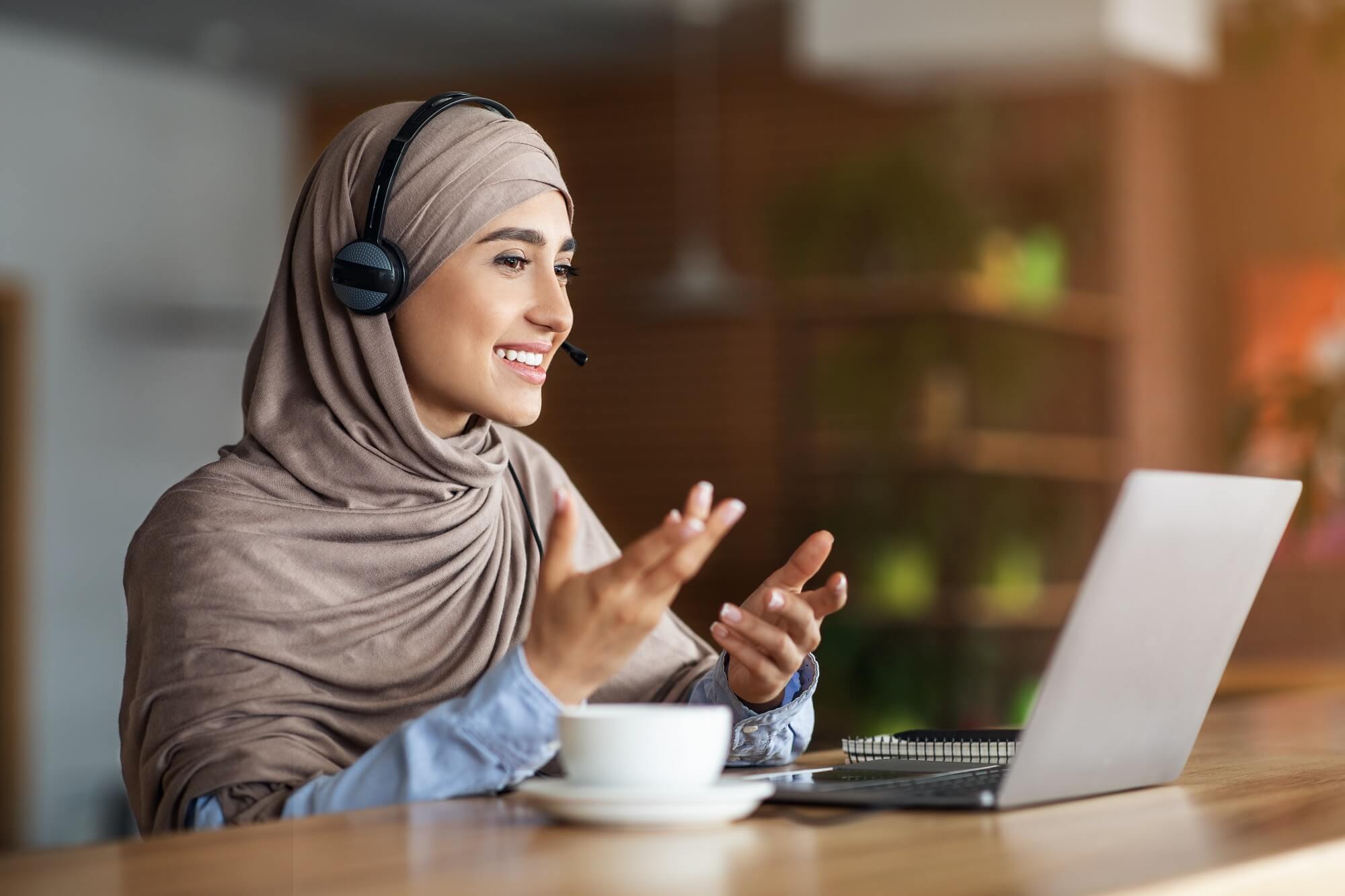 women doing virtual event planning at cafe, using headset and laptop